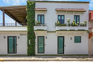 A two-story building with a balcony on the upper floor, a green vertical garden on the left, and a number '2009' on the facade. - Costa Brava Apt 1 | Calle Loiza Cozy @ San Juan (San Juan de Puerto Rico)