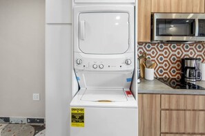 A compact kitchen with a washing machine, microwave, and coffee maker. - Costa Brava Apt 1 | Calle Loiza Cozy @ San Juan (San Juan de Puerto Rico)