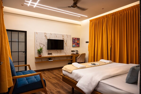 A hotel room with a bed, a desk, a chair, a television, and a window with curtains.