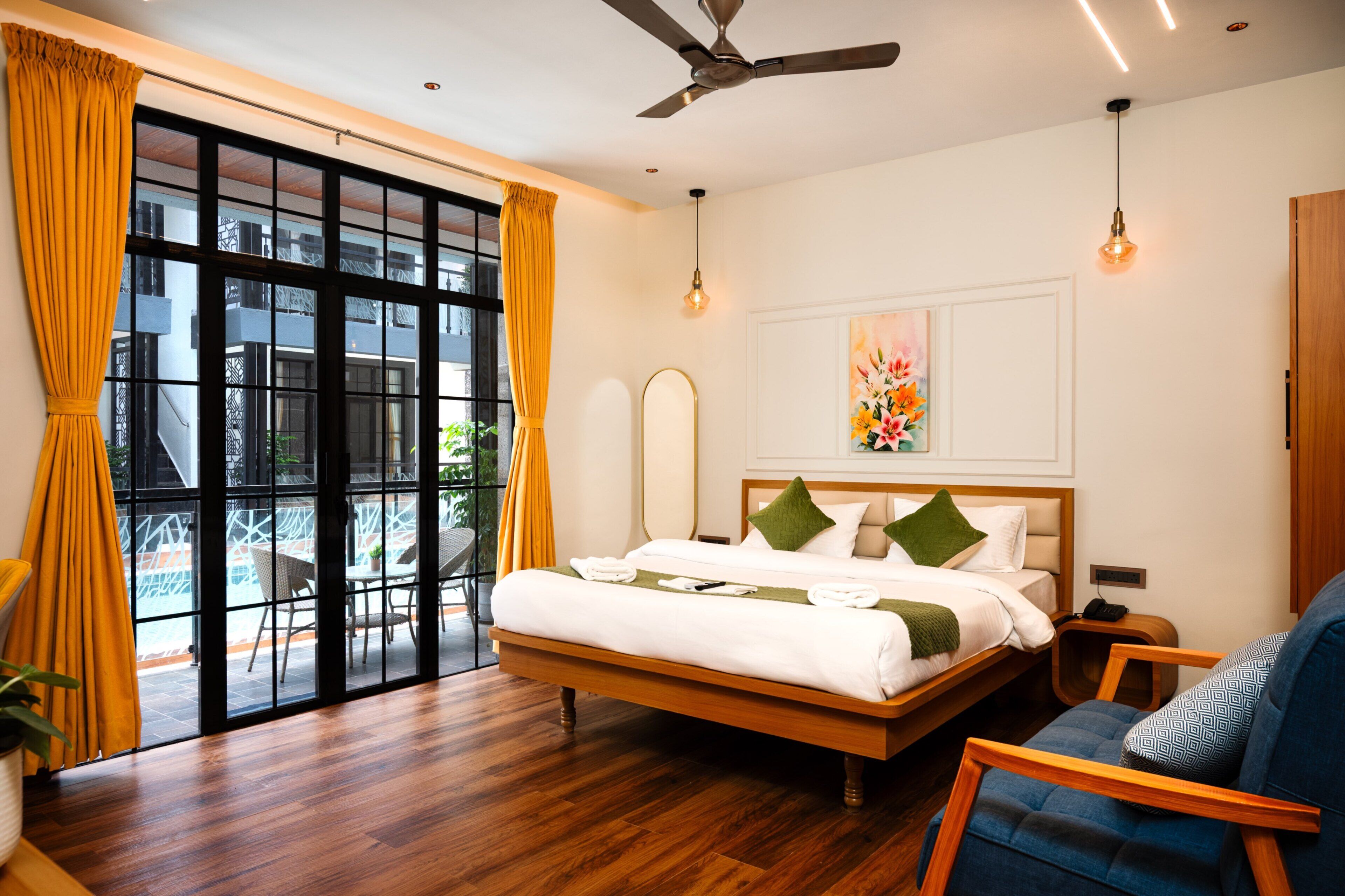 A hotel room with a large bed, a seating area, and a view through a sliding door.