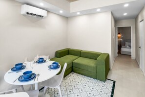 A modern room with a dining area, a green sofa, and a patterned rug. - Costa Brava Apt 2 | Calle Loiza 2 Bed @ San Juan (San Juan de Puerto Rico)