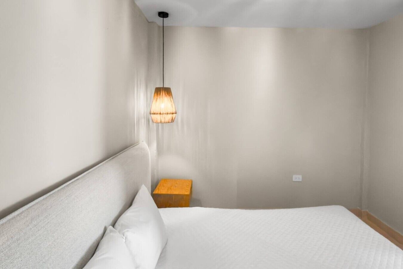 Een hotelkamer met een bed, een nachtkastje en een hanglamp.