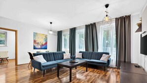 Un salon moderne avec un canapé d’angle, une table basse et un téléviseur à écran plat.