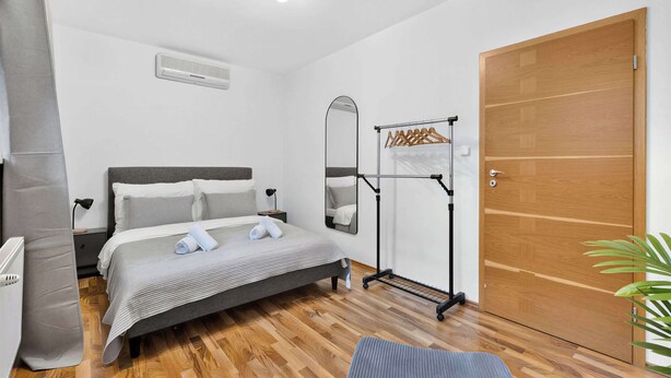 Une chambre à coucher comprenant un lit, une table de chevet, un miroir, une armoire et un radiateur.