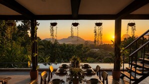 A dining table set for four with a view of a sunset and mountains.