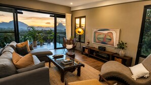 A modern living room with a sofa, armchair, coffee table, and a painting on the wall.