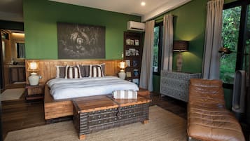 A bedroom with a bed, bedside tables, a reading chair, and a large window with curtains.