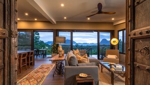 A spacious living area with a sofa, coffee table, and a view of the mountains through large windows.
