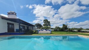 Una piscina con un cielo azul despejado y nubes al fondo.