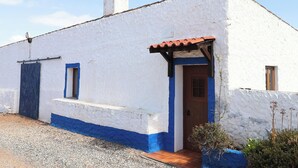Un edificio blanco con puerta azul y una ventana pequeña.