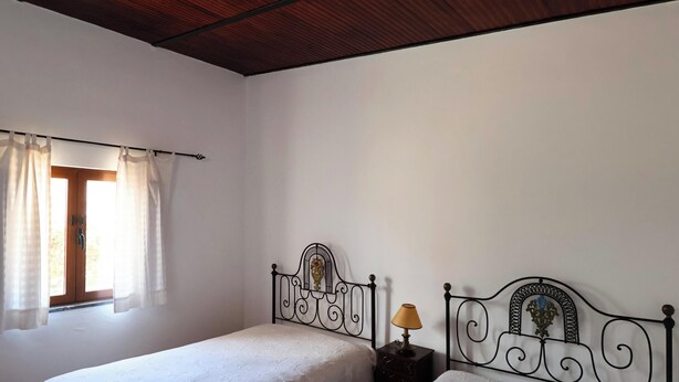 Un dormitorio con una cama individual, una mesita de noche, una lámpara y una ventana con cortinas.