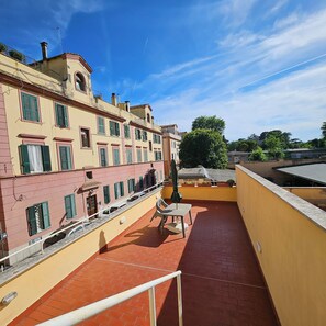 A rooftop terrace with a view of adjacent buildings, a railing, and a table with chairs. - A charming, stylish open-concept space (Roma)