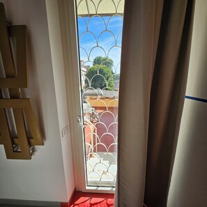 A doorway with a metal gate leading to an outdoor area with a red floor and a white railing. - A charming, stylish open-concept space (Roma)