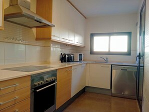 Eine moderne Küche mit weißen Schränken, einem Edelstahlbackofen, einer Mikrowelle und einem Geschirrspüler.