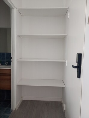 A white interior with three shelves and a door with a black handle. - Acogedor departamento en Villa Urquiza (Buenos Aires)