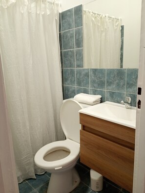 A bathroom with a toilet, a sink, and a shower curtain. - Acogedor departamento en Villa Urquiza (Buenos Aires)