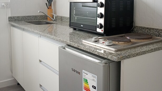 Eine Küche mit eingebautem Toaster, einer Arbeitsplatte aus Granit und einem Edelstahl-Kühlschrank.