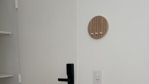 Eine weiße Tür mit schwarzem Griff, eine weiße Steckdose und ein an der Wand befestigtes Holzobjekt.