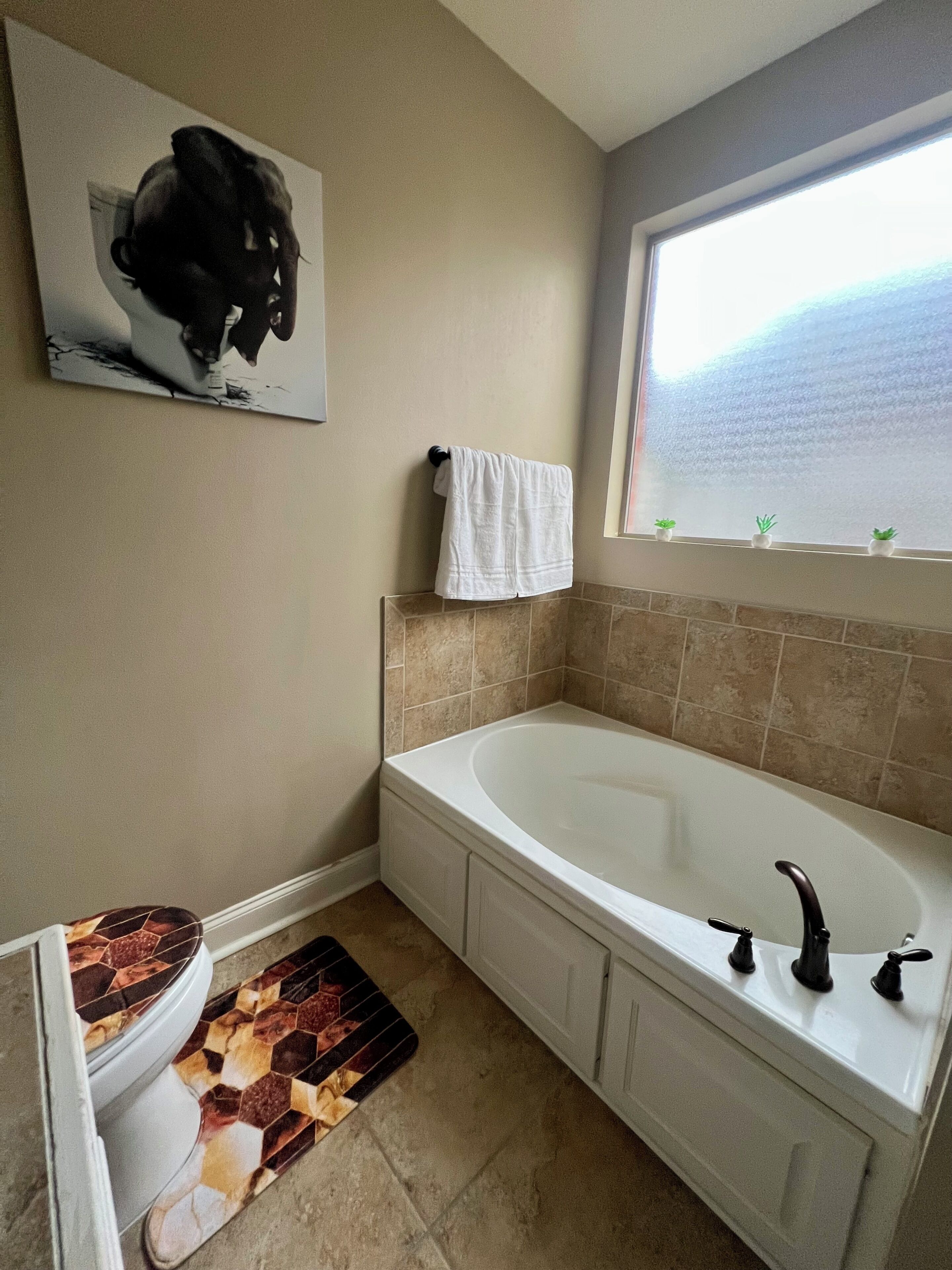 Un baño con bañera, inodoro y ventana con vistas.