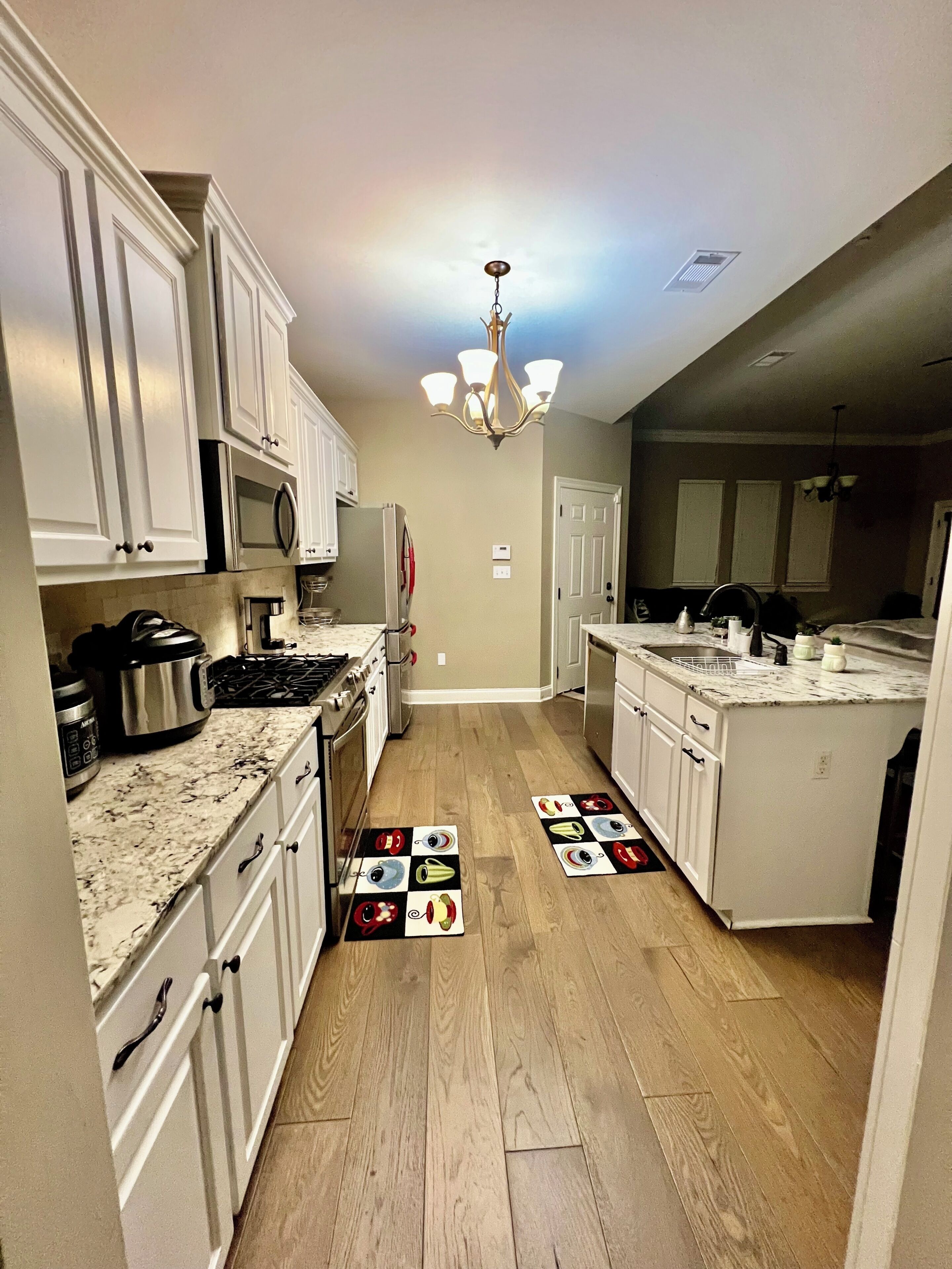 A kitchen with white cabinets, a microwave, a stove, and a chandelier.