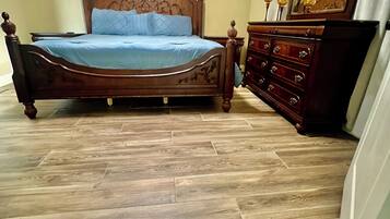 A bedroom with a wooden bed, a dresser, and a mirror.