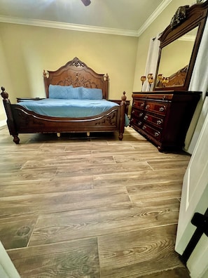A bedroom with a wooden bed, a dresser, and a mirror. - 3-bedroom house in nice Gonzales with cool AC comfort (Gonzales)