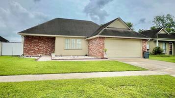 A single-story house with a brick facade, a garage, and a well-maintained lawn.