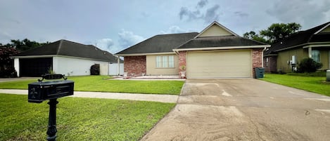 A residential driveway leading to a house with a garage, a mailbox, and a well-maintained lawn.