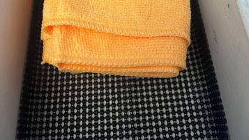 A white drawer with a black textured mat at the bottom and a folded yellow towel on top.