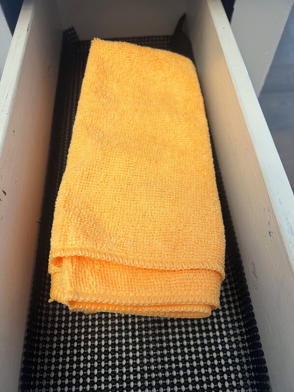 A white drawer with a black textured mat at the bottom and a folded yellow towel on top. - 3-bedroom house in nice Gonzales with cool AC comfort (Gonzales)