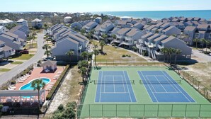 Ett bostadsområde med flera tvåvåningshus, en tennisbana och en swimmingpool.