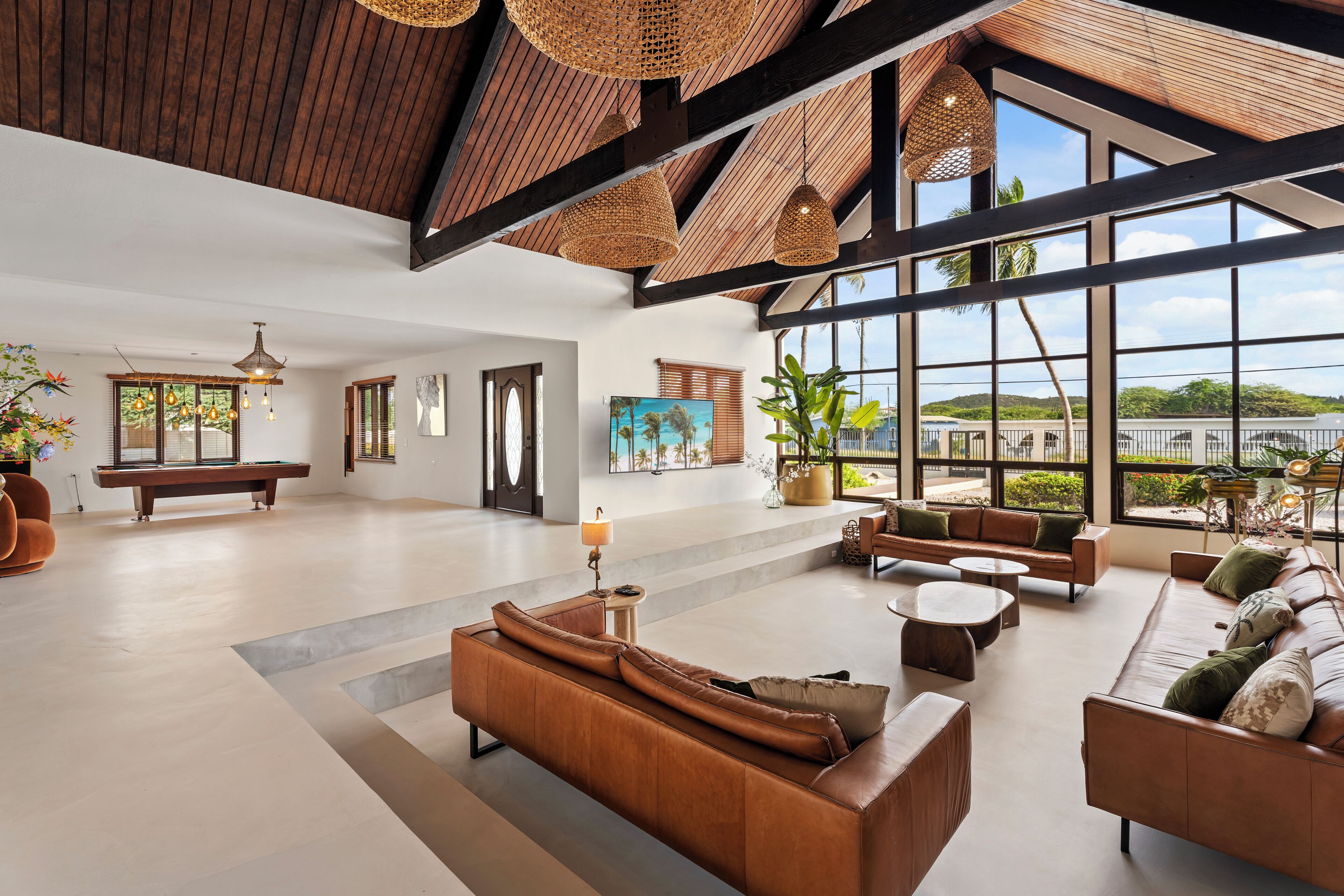 A spacious lobby with a high ceiling, large windows, and a pool table.