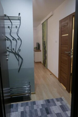 A hallway with a wooden door, a patterned rug, and a wall-mounted light fixture. - Green Dream Polanki - Sauna & Bicycle & Bicycle (Kołobrzeg)