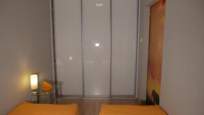 Une pièce comprenant un lit, une table de chevet, une lampe et un tableau accroché au mur.