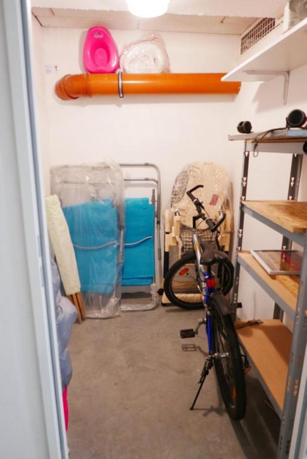 Una habitación con bicicleta, una silla y estante con objetos.