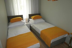 A room with two single beds, each with a white mattress and an orange blanket. - Green Dream Polanki - Sauna & Bicycle & Bicycle (Kołobrzeg)
