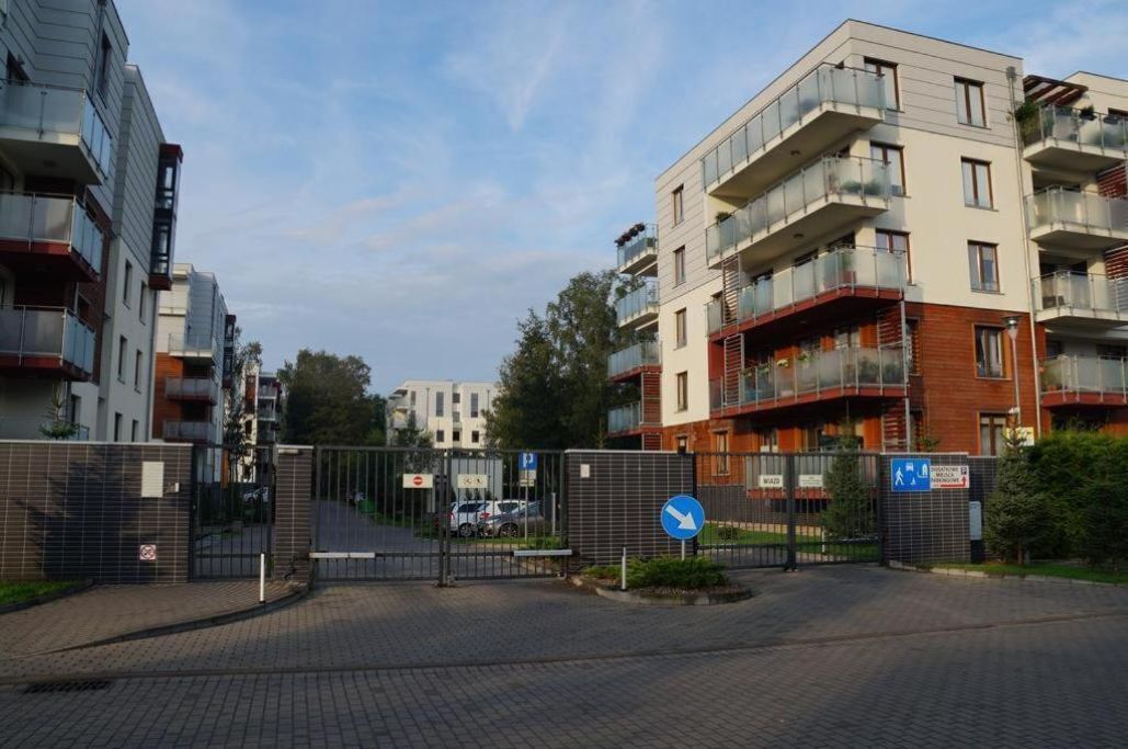 A gated residential complex with modern architecture, featuring balconies and a clear sky.