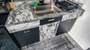 A kitchen with a marble countertop, a sink, and a dish rack. - The River Condos (Detroit)