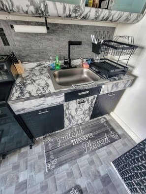 A kitchen with a marble countertop, a sink, and a dish rack. - The River Condos (Detroit)