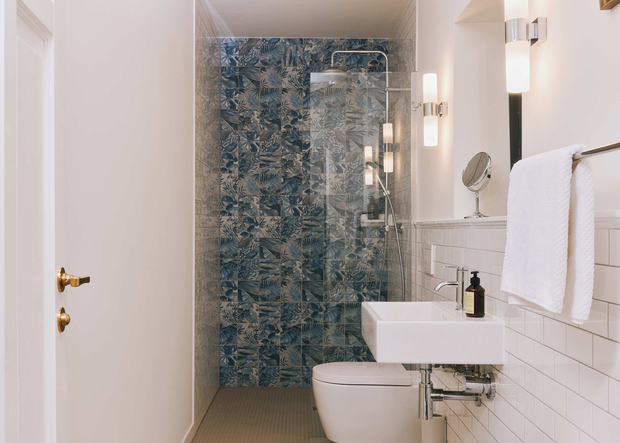 Een badkamer met douche, toilet, wastafel en spiegel.