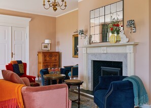 Una sala de estar con chimenea, espejo y una silla roja.
