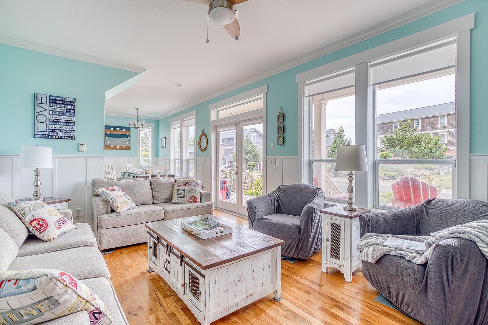 Sink into plush seating in your bright coastal living room, where soft sea-foam walls and sunny windows frame your peaceful neighborhood retreat.