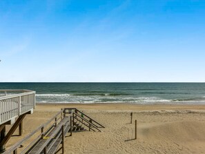 Una pasarela de madera que lleva a una playa con vistas despejadas del océano.
