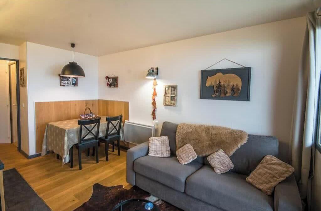 A cozy living area with a sofa, a dining table with chairs, a pendant light, and wall art.