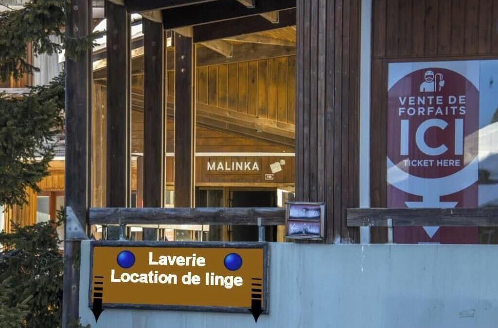 L’entrée d’un immeuble avec une enseigne indiquant la présence d’une laverie.