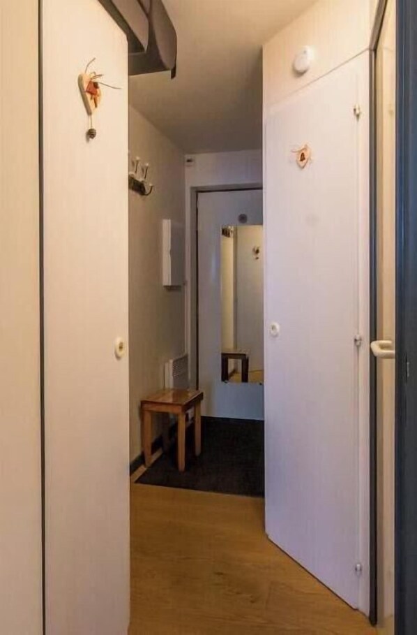 A narrow hallway with a wooden floor, a small table, and a door with a handle.