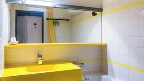 Un baño con un lavabo amarillo, una bañera y un espejo.