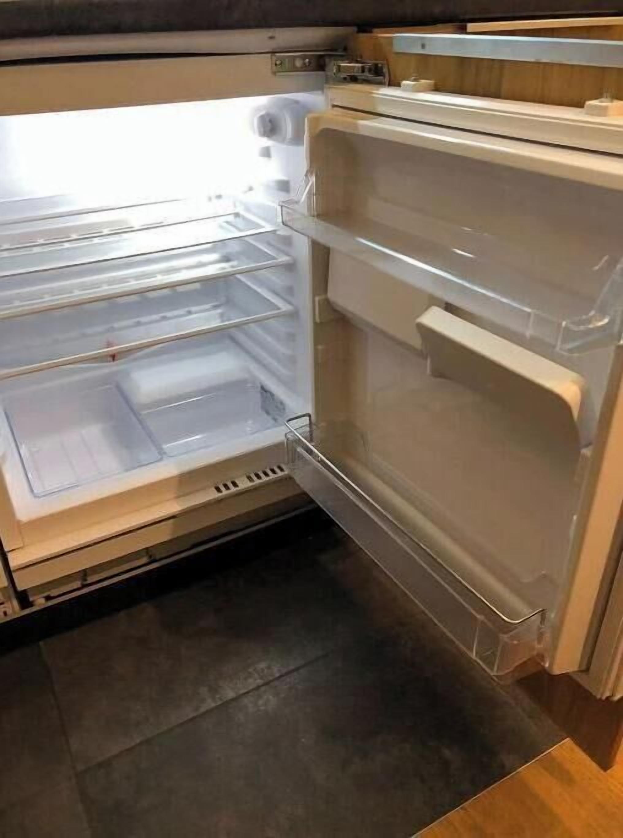 Un refrigerador abierto con varios estantes y un compartimento congelador.