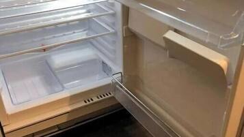 Un refrigerador abierto con varios estantes y un compartimento congelador.