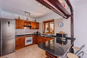 Una cocina con armarios de madera, un refrigerador de acero inoxidable, un microondas y una isla grande con taburetes.